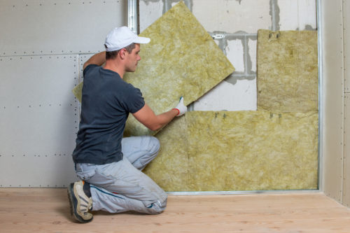 artisan installant de l’isolant thermique sur un mur dans une maison, selon la RT2020 isolation mur