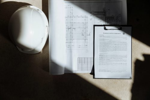 Plan de construction et casque de chantier pour vérifier le Bbio RT2012 avant le dépôt du permis