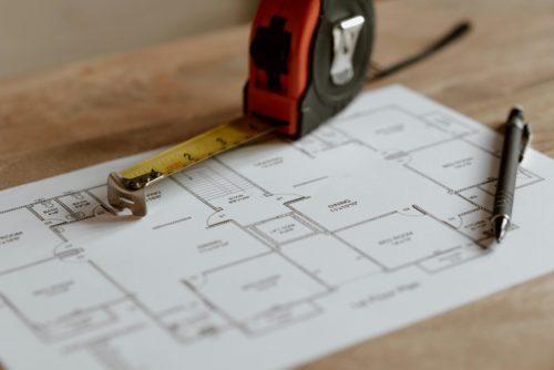 Plan de maison avec mètre ruban pour préparer un dossier RE2020 et un permis de construire conforme