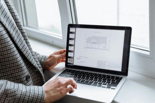 Consultation de plans de maison sur ordinateur pour vérifier l’application RE2020 d’un projet de construction