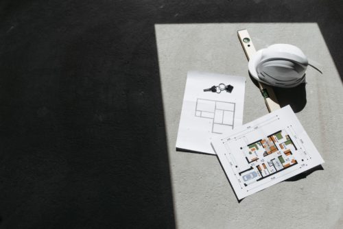 Plans de construction, casque de chantier et niveau à bulle posés sur une dalle, illustrant la validation de conformité en fin de travaux RT 2012