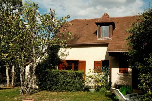 Maison individuelle avec volets en bois et jardin arboré représentant un logement construit sous la réglementation thermique RT 2012