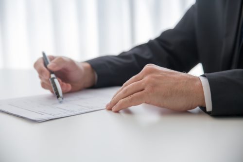 Professionnel signant un document réglementaire illustrant les obligations de conformité liées à la RE2020