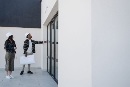 RE2020 permis de construire : deux professionnels casqués inspectant une façade avec les plans du projet