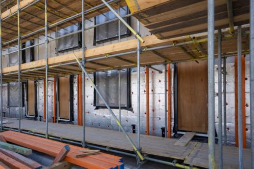 Chantier de construction avec pose de panneaux isolants réfléchissants sur les murs extérieurs pour atteindre la résistance thermique R recommandée